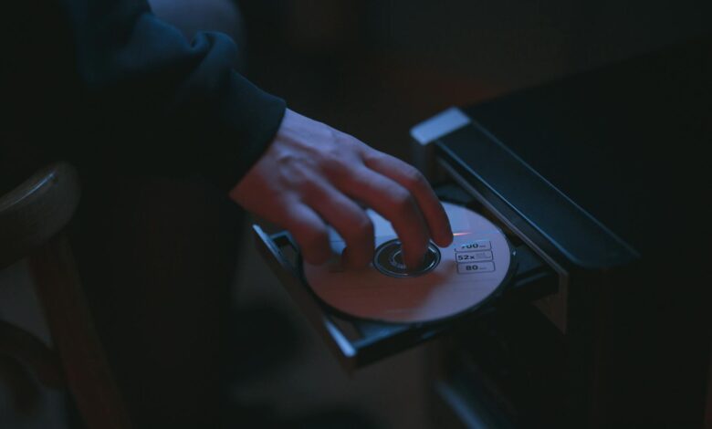 A hand inserting a CD into a computer drive, highlighting cyber security themes.