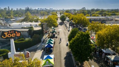 Aerial shot of a lively street market under blue skies in Sacramento with vendor tents and people.