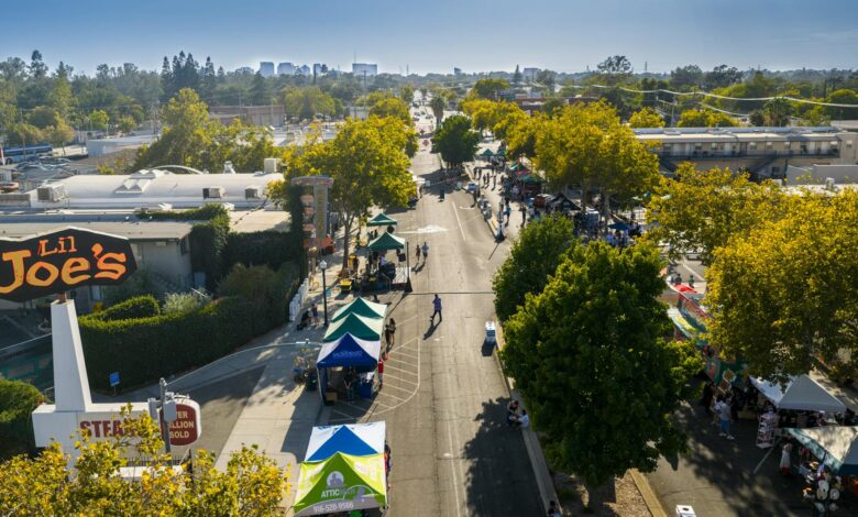 Aerial shot of a lively street market under blue skies in Sacramento with vendor tents and people.