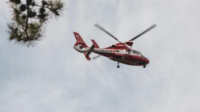 Red and white rescue helicopter flying in the sky, captured outdoors.