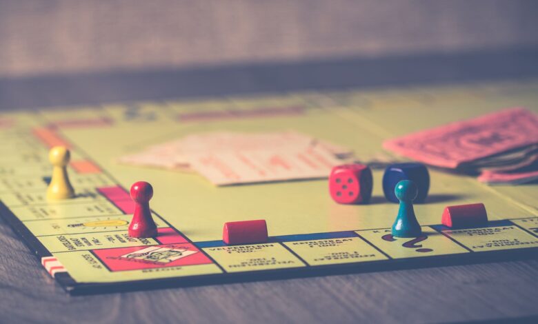A close-up of a Monopoly board game with pieces and dice scattered around.