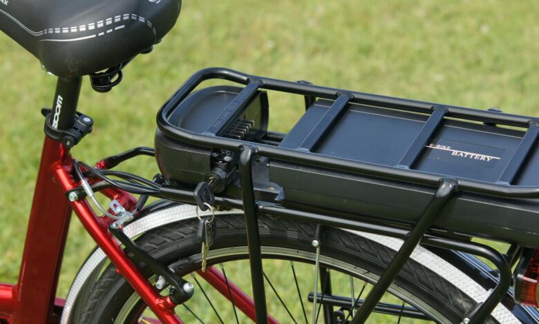 Detailed view of an electric bicycle battery mounted on a rear rack, highlighting the key-lock mechanism.