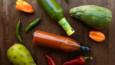 Vibrant display of hot sauces and peppers on a wooden surface, perfect for culinary themes.