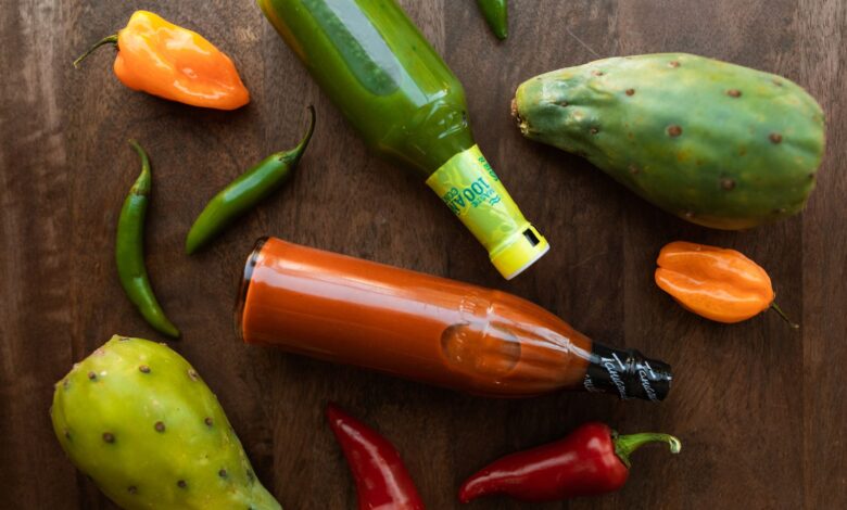Vibrant display of hot sauces and peppers on a wooden surface, perfect for culinary themes.