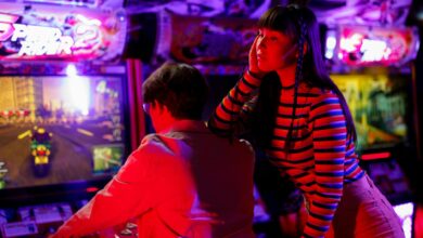 Couple engaged in vibrant arcade gaming with neon lights and racing excitement.