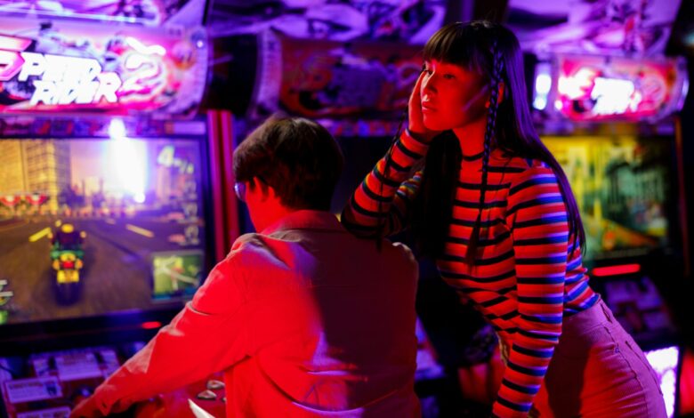 Couple engaged in vibrant arcade gaming with neon lights and racing excitement.