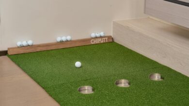 Indoor putting green with golf balls and equipment for golf practice at home.