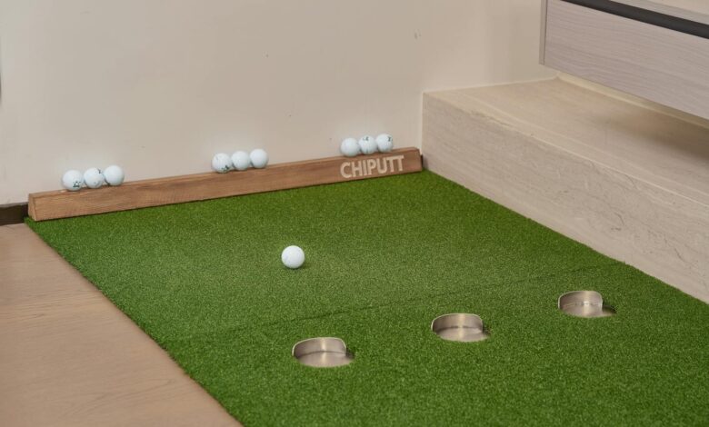 Indoor putting green with golf balls and equipment for golf practice at home.