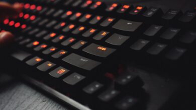 Detailed view of a gaming keyboard with backlit keys and glowing red lights.