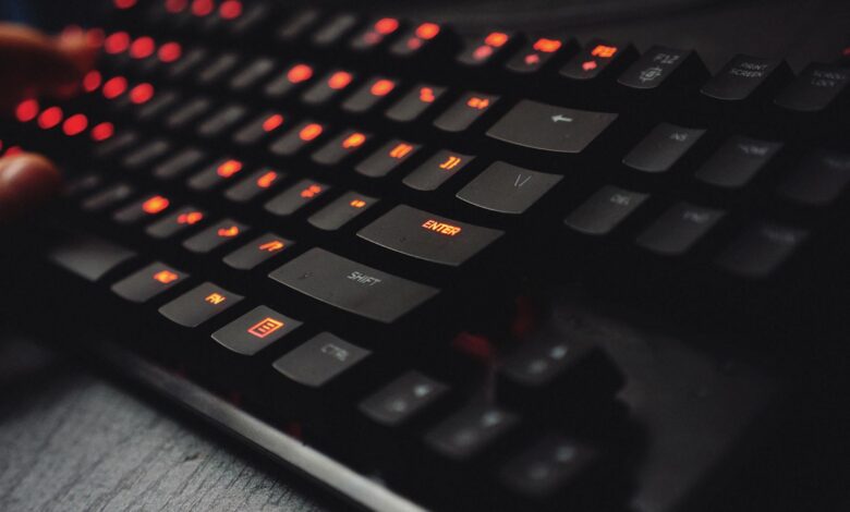 Detailed view of a gaming keyboard with backlit keys and glowing red lights.