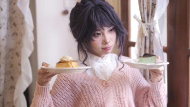 A young woman in a cozy setting holds plates with pastries, looking contemplative.