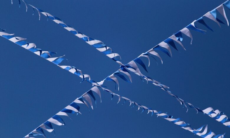 Photo of blue and white streamers crisscrossing a clear blue sky.
