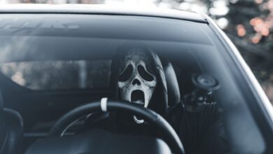 Masked individual in car adds an eerie vibe, suitable for Halloween themes.
