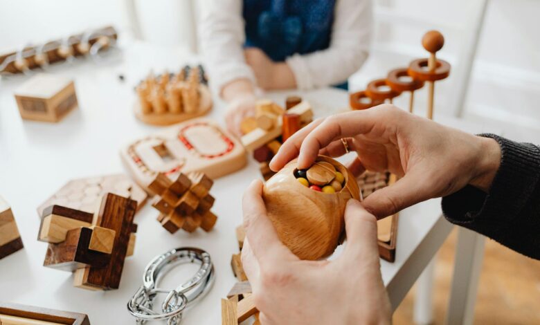 Close-up of hands engaging with wooden brain teasers on a table indoors.