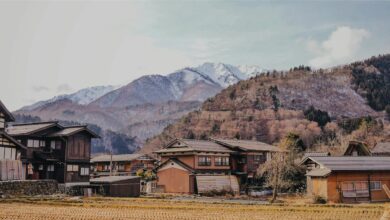 Scenic view of a traditional Japanese village with mountains in the background during winter.