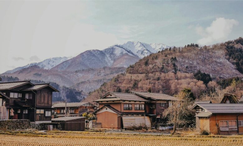 Scenic view of a traditional Japanese village with mountains in the background during winter.