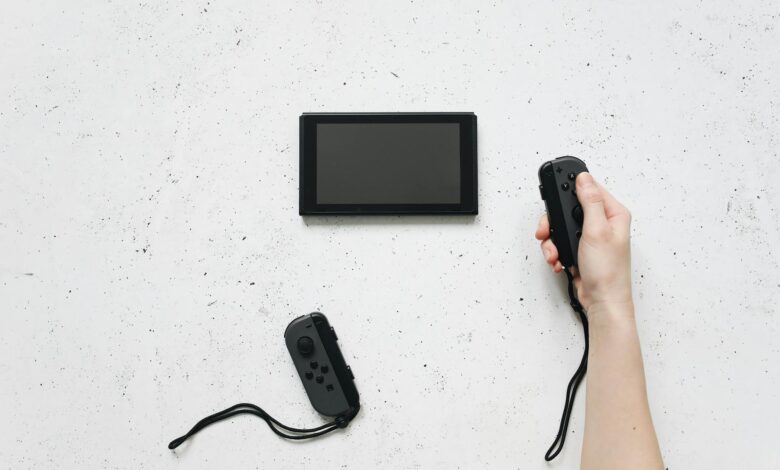 A person holds a Joy-Con controller with a Nintendo Switch on a white textured surface.