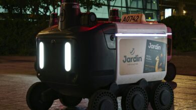 Close-up view of an autonomous delivery robot on a city street at night under artificial light.