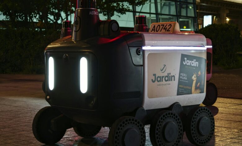 Close-up view of an autonomous delivery robot on a city street at night under artificial light.