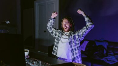 Joyful gamer celebrating victory while playing video games at night, wearing headphones.
