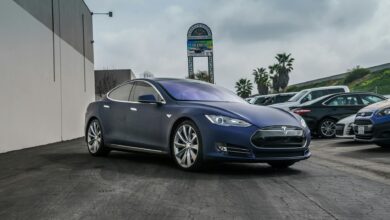 A sleek navy blue Tesla Model S electric vehicle parked in an urban setting.