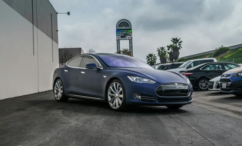 A sleek navy blue Tesla Model S electric vehicle parked in an urban setting.