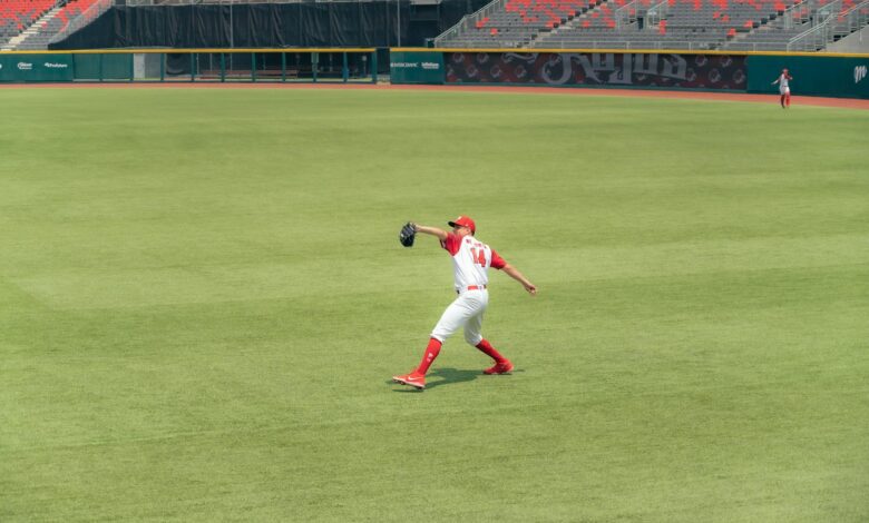 Athlete in action making a catch on green field in an empty stadium.