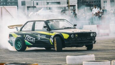 Dynamic car drifting scene with a crowd of spectators in an outdoor event setting.