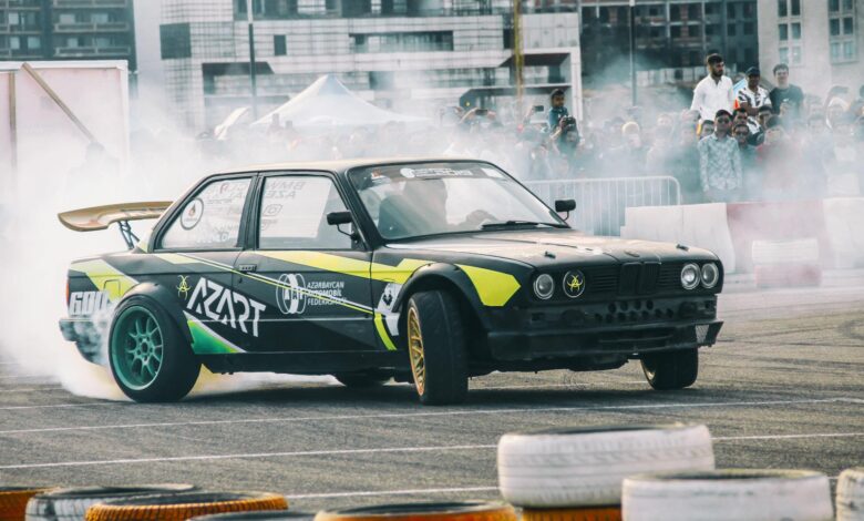 Dynamic car drifting scene with a crowd of spectators in an outdoor event setting.