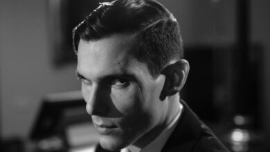 Cinematic black and white portrait of a serious man with a scar and intense expression.