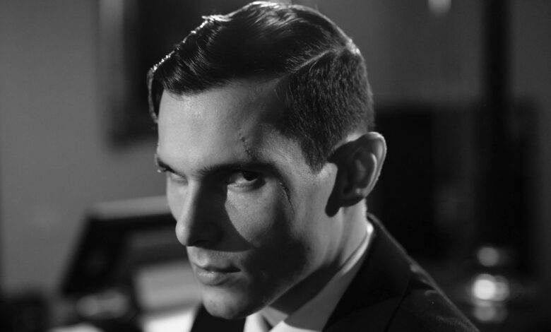 Cinematic black and white portrait of a serious man with a scar and intense expression.