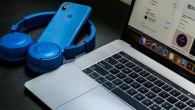A sleek office setup featuring a laptop, blue headphones, and a smartphone, exemplifying modern technology.