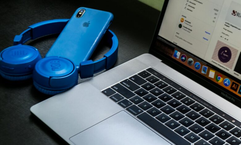 A sleek office setup featuring a laptop, blue headphones, and a smartphone, exemplifying modern technology.