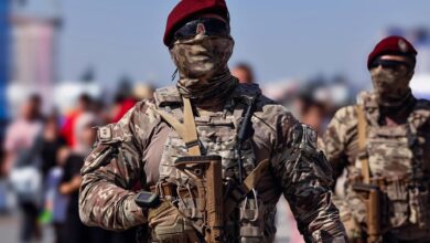 Armed Turkish commandos in camouflage gear marching outdoors during the day.
