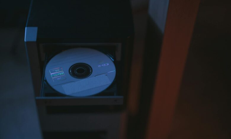 A close-up image of a CD partially ejected from a drive, showcasing soft lighting.
