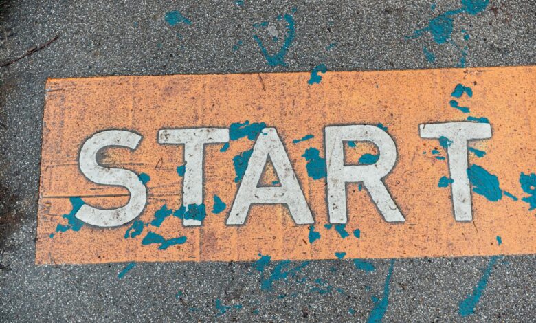 A worn orange start line painted on urban pavement with blue splatters.
