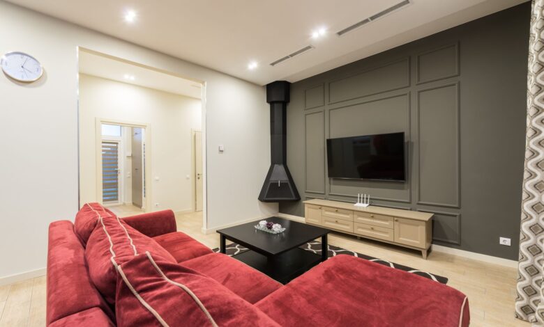 Interior of modern large living room with TV hanging on gray wall illuminated with bright lamps