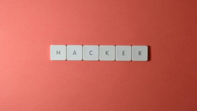 Close-up of the word 'HACKER' made with letter tiles on a red background, emphasizing cybersecurity.