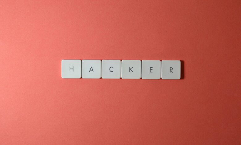 Close-up of the word 'HACKER' made with letter tiles on a red background, emphasizing cybersecurity.