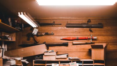 Interior of an armory with wooden walls, weapons, and equipment stored in boxes.