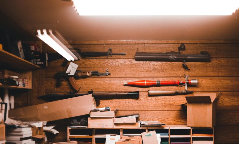 Interior of an armory with wooden walls, weapons, and equipment stored in boxes.