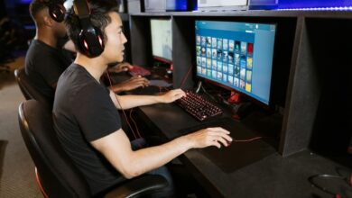 Two young men play video games at a cyber cafe, showcasing modern gaming technology indoors.