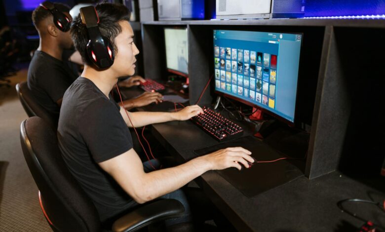 Two young men play video games at a cyber cafe, showcasing modern gaming technology indoors.