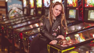 A woman in a leather jacket enjoying a moment at a vintage pinball arcade.