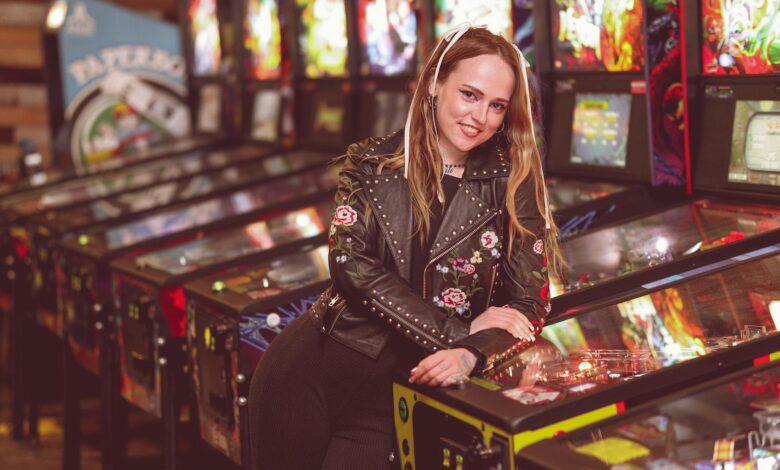 A woman in a leather jacket enjoying a moment at a vintage pinball arcade.