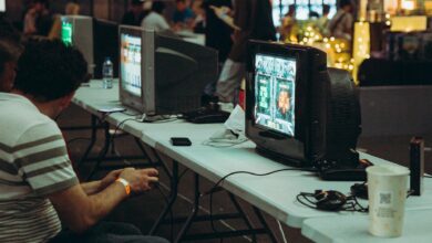 Adults enjoying a retro gaming event with CRT televisions and consoles, creating a nostalgic atmosphere indoors.