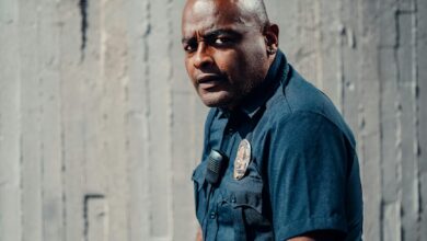 A police officer in uniform standing confidently outdoors, looking sideways, conveying authority.