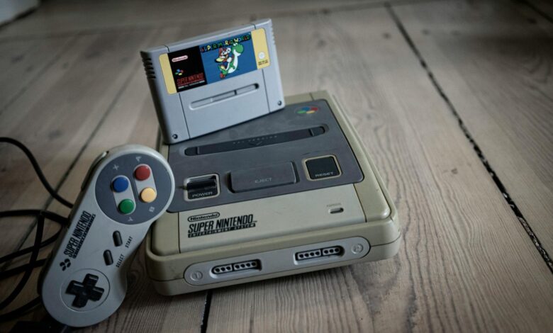 From above of aged video game console with cassette and controller with colorful buttons on wooden surface