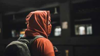 Portrait of an adult in a Spider-Man costume carrying a backpack in an urban subway station.