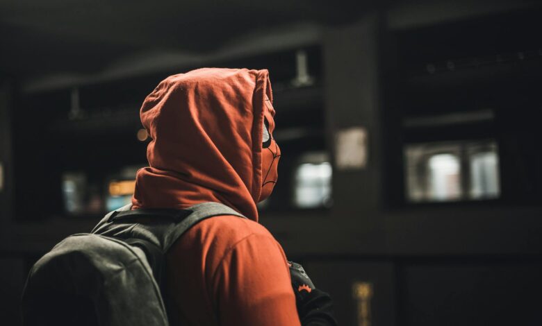 Portrait of an adult in a Spider-Man costume carrying a backpack in an urban subway station.